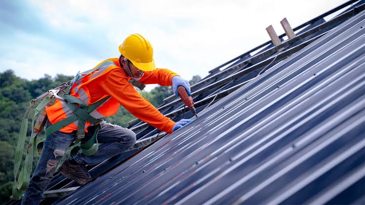 Commercial roof repairs Adelaide — technician replacing corroded fasteners on a metal deck warehouse roof